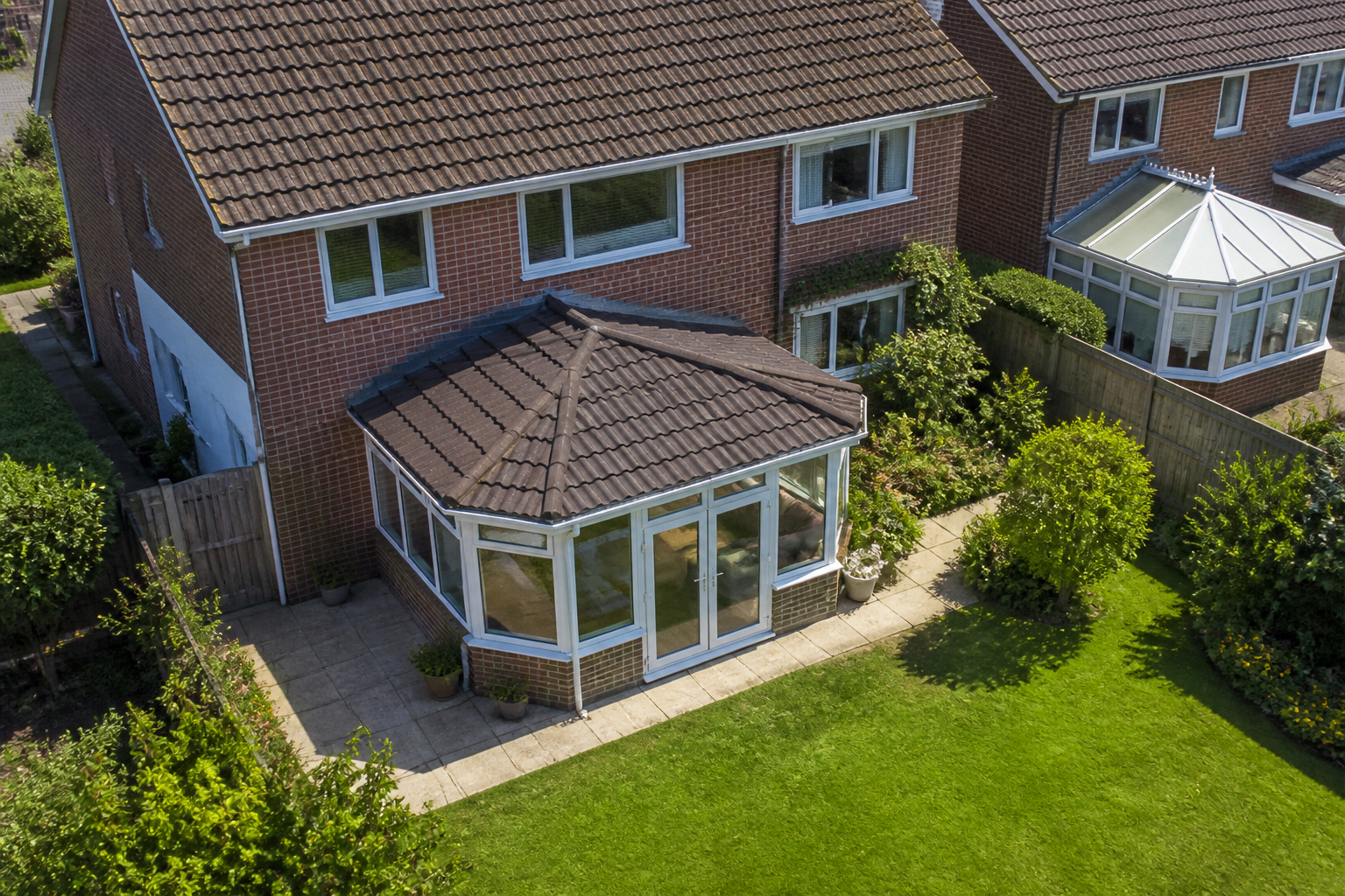 Exterior view of a home with a modern conservatory featuring a SupaLite™ tiled warm roof, blending seamlessly with the…