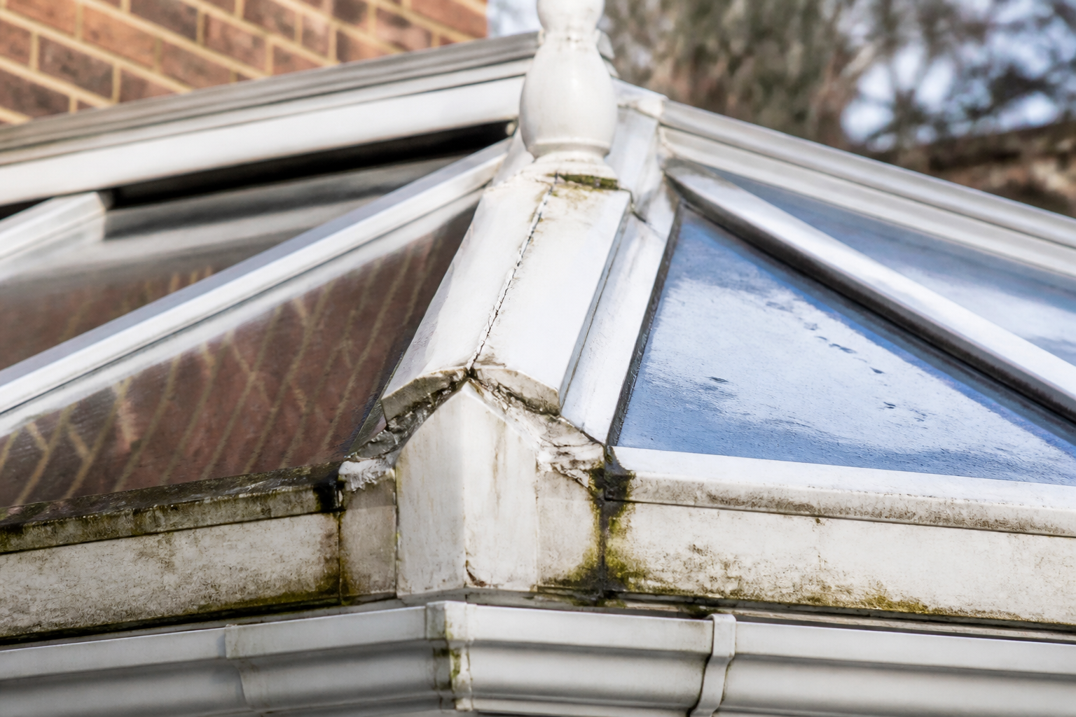 Close-up of a failing conservatory roof sealant, showing cracks, discolouration, and water ingress.